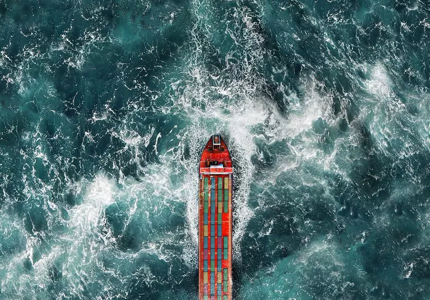 An overhead view of a cargo vessel moving through ocean water